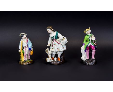 Three Various Fairing Figures comprising a girl carrying a basket from which she is feeding a begging spaniel, a rotating clo