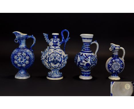 Four Various Small Westerwald Ewers, one with grape and vine decoration and bird mask spout, 7.5 inches high, one with winged
