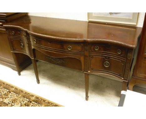 An Edwardian mahogany serpentine fronted sideboard in the Chippendale revival taste with two central drawers flanked by a cup