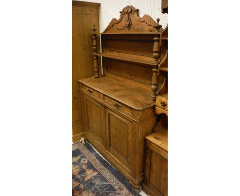 A pine chiffonier with open shelves above two drawers and two cupboard doors, on bracket feet