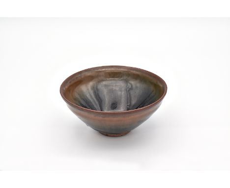 The conical bowl covered in a running russet and olive-black glaze falling short of the foot, exposing the unglazed purplish 