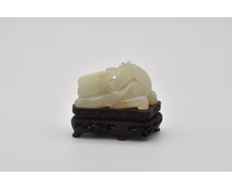 Modelled rolling on its back, the stone with russet inclusions, wooden stand (2)Length: 5.5cmCondition ReportThe celadon jade