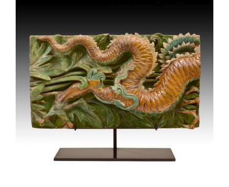 The coiled striding dragon carved in high-relief coloured in turquoise, ochre and green glazes, on black-metal stands   Lengt