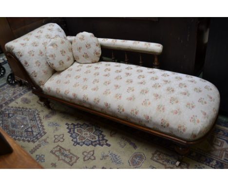 A Victorian mahogany chaise, scrolling arm, padded top rail, spindle back, stuffed overseat, turned legs, ceramic casters.