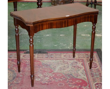 A mahogany reproduction card table, serpentine fold over top, reeded edge, inlaid green leather playing surface, tapering flu