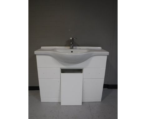 A ceramic hand basin with tap, together with a white high gloss sink unit 