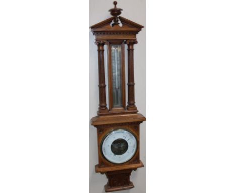 An Edwardian oak cased barometer and thermometer, the 19cm dia. dial with Arabic numerals and a thermometer flanked by carved