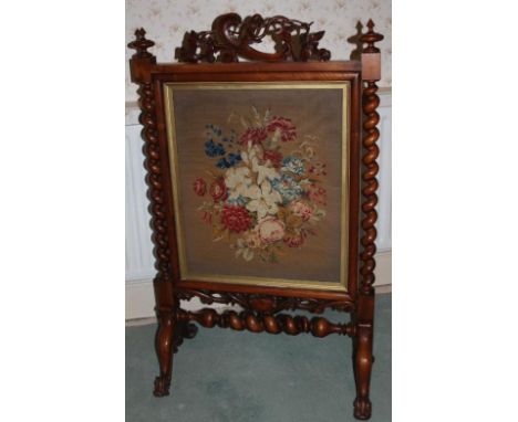 A Victorian mahogany firescreen, with carved pediment, barleytwist framing and scroll legs and a floral Berlin woolwork panel
