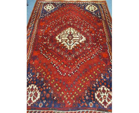 AN EASTERN STYLE RED GROUND WOOLLEN CARPET with central light colour block on a red ground with blue corners and multi-border