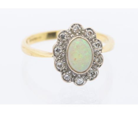 An opal and diamond set 18ct gold ring, set with an oval opal within a border of small diamonds, setting width approx 8mm, si