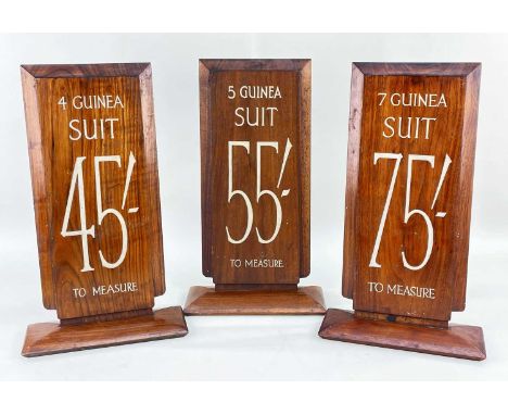 THREE VINTAGE WALNUT TAILOR'S SIGNS, for suits priced 4, 5 and 7 guineas and measuring costs in shillings, 47 x 20.5cm (3)