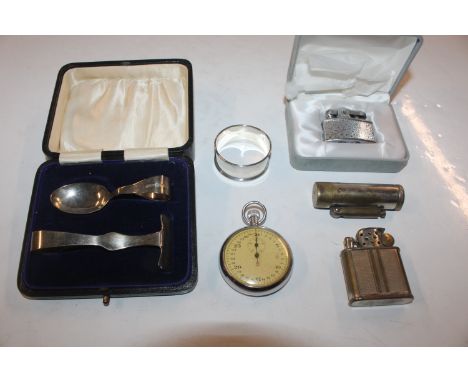 A stopwatch; a collection of cigarette lighters; a silver feeding spoon and pusher and a silver napkin ring