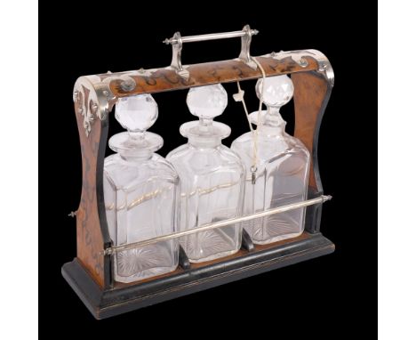 A Victorian Gothic silver plate mounted ebonised burr-walnut 3-bottle tantalus, with 3 fitted square glass decanters, all uns