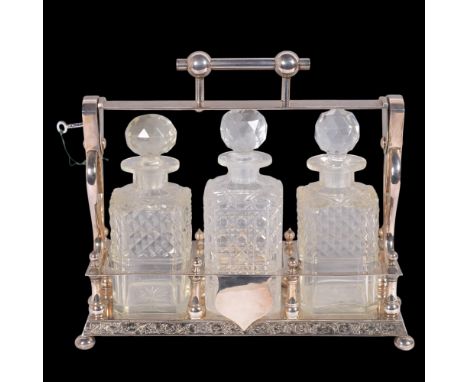 A Victorian Aesthetic Movement silver plated 3-bottle tantalus, L36cm, with key1 decanter is not matching, all 3 have tiny ch
