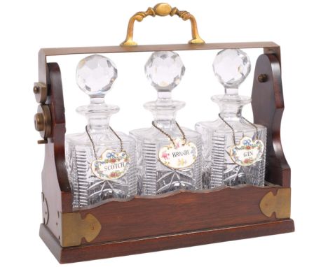 A stained beech and brass-mounted 3-bottle tantalus, with glass decanters and stoppers, and Staffordshire ceramic decanter la