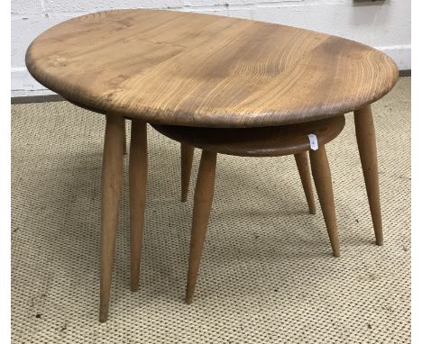 An Ercol elm nest of three pebble tables on three turned splayed supports, the largest 65 cm x 44 cm x 40.5 cm together with 