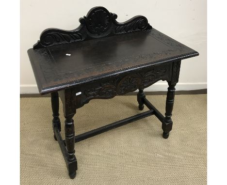 A carved oak Gothic Revival style side table on turned legs united by a centre stretcher 83 cm wide x 42.5 cm deep x 88 cm hi