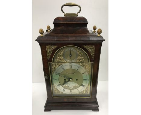 A George III mahogany cased mantle clock, the caddy top with brass handle and pineapple finials, the arched glazed door with 