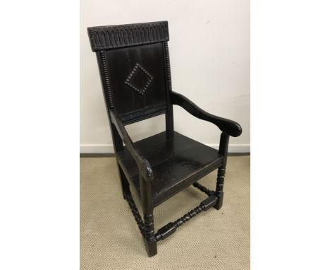 An oak Wainscott type armchair in the 17th Century style with carved top rail over a panelled back with bobbin lozenge design