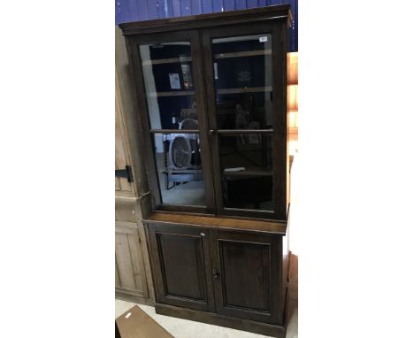 An oak bookcase cabinet in the Georgian style, the moulded cornice over two glazed doors enclosing adjustable shelving on a b