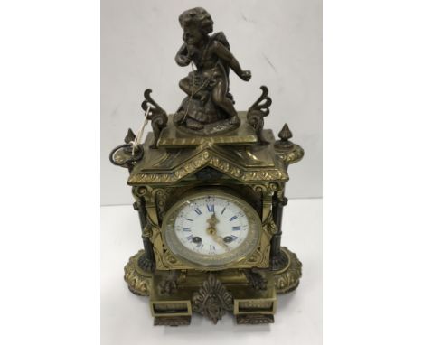 A 19th Century brass cased French mantel clock, the top set with putti and scrolling decoration with pillar supports, the whi