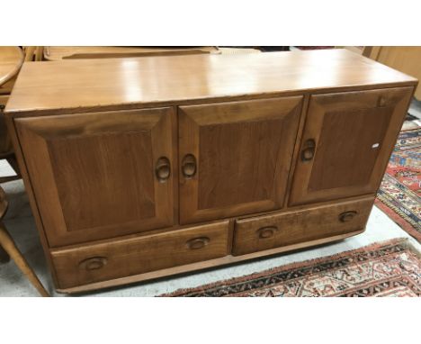 An Ercol elm "Windsor" sideboard, the plain top over three cupboard doors and two drawers on ball castors 129 cm wide x 44 cm