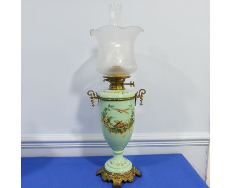 An Edwardian glass and gilt-metal oil lamp, with&nbsp; moulded shade above a green opaque oviform lamp base enamelled with fl