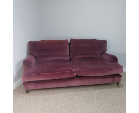 A good quality Howard style, club two seater sofa, upholstered in purple with some fading near the top cushions, upon four le