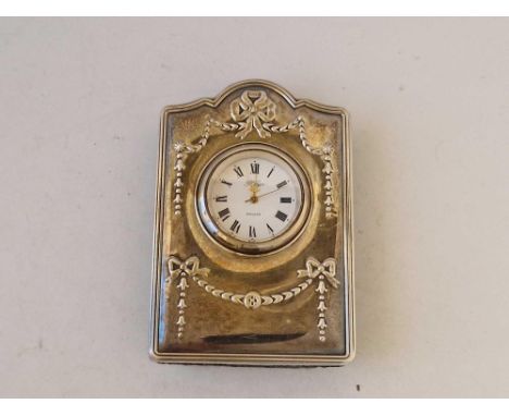 A silver cased travelling clock with embossed ribbon decoration, 3.5" high