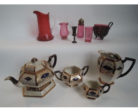 A Victorian cranberry glass jug with textured finish and high clear glass handle, a further cranberry glass shaker with plate