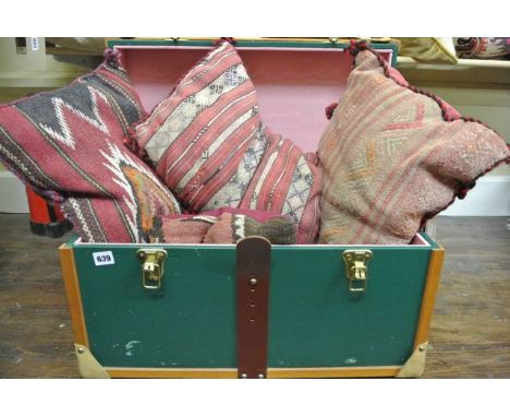 A small green and timber banded travel trunk containing a selection of Kelim upholstered cushions