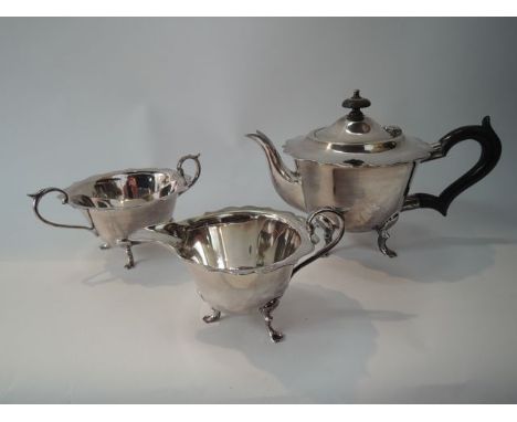 An electroplated three piece tea set to include a teapot raised on four swept supports with shaped outline, hinged cover with