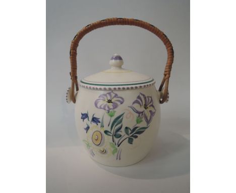 A Poole Pottery biscuit barrel and cover with rattan handle, painted blue, green and yellow floral decoration with printed ma