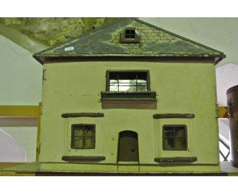 An unusual vintage dolls house constructed in tin, the triangular roof set with a window above a hinged and opening façade co