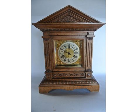 A late 19th century oak bracket clock of architectural form with brass dial and silvered chapter ring and gong striking movem