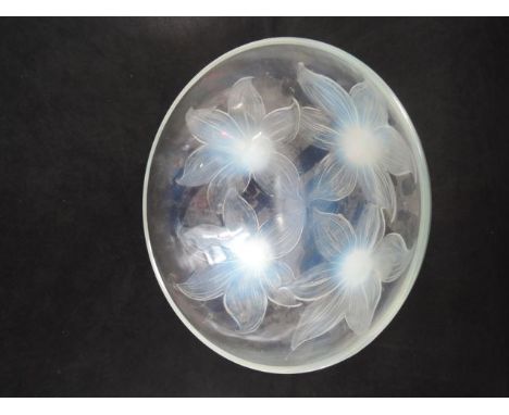 A pressed glass bowl  raised on four supports in the form of flower heads with petal decoration in relief, with Vaseline tint