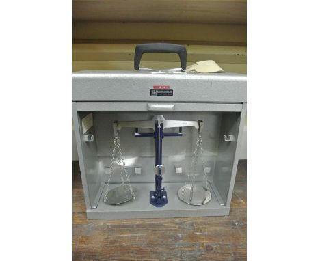 A set of beam scales to a capacity of 20 grams in a metallic finished case with tambour front, County of Avon