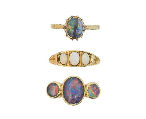 Three opal dress rings, to include an 18ct gold opal three stone ring, an 18ct gold opal triplet three stone ring, and a boul