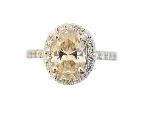 An 18ct gold diamond cluster ring, the oval cut diamond weighing approx. 1.55cts, estimated colour tinted, estimated clarity 