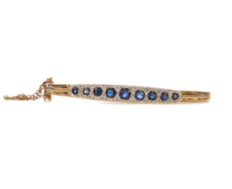 SAPPHIRE AND DIAMOND BANGLE, set with round sapphires interspaced by pairs of diamonds, with scrollwork and engraved decorati