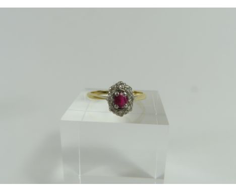 A ruby and diamond cluster ring, the oval cut ruby in a four claw setting with a row of round diamonds around it, marked '18c