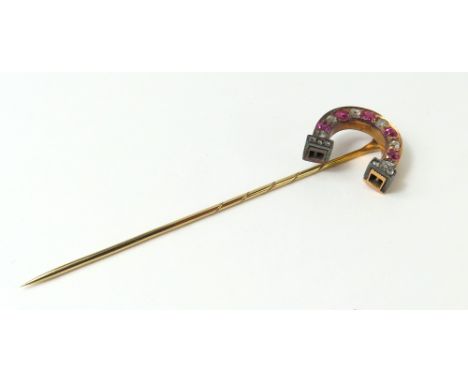 A 19th or early 20th century stick pin, the top in the form of a horseshoe set with rubies and old cut diamonds, the ends of 