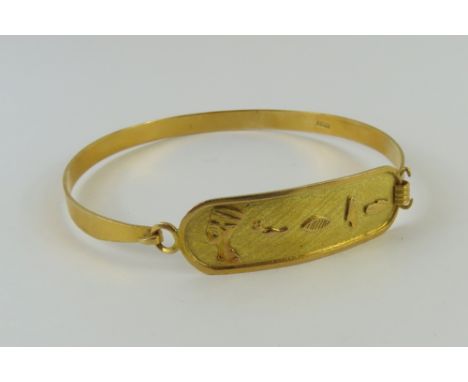 A solid gold bangle with ID type cartouche to the centre, with hieroglyphic symbols, 6.3cm internal diameter, bears control m