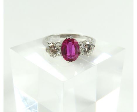 A 20th century pink sapphire/ruby and diamond three stone ring, the oval cut pink sapphire/ruby with a round cut diamond to e