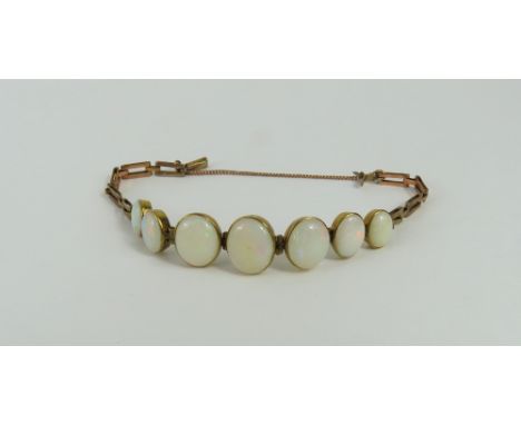 A late 19th or early 20th century white opal bracelet, the seven graduated cabochon cut opals in rub over settings, with bar 