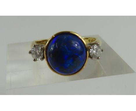 An 18ct gold black opal and diamond three stone ring, the round cabochon cut opal rub over set with a round brilliant cut dia
