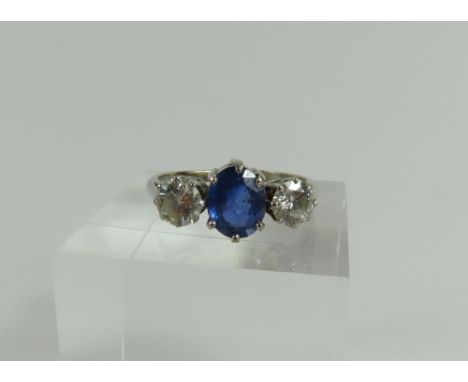 An 18ct white gold sapphire and diamond three stone ring, the oval cut sapphire in a six claw setting, approximately 7mm x 8.