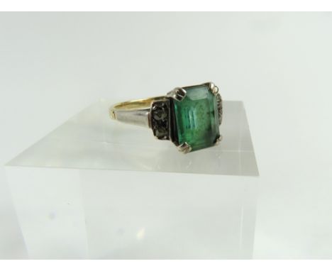 An early 20th century emerald and diamond ring, the step cut emerald in double claw settings, with a pair of small rose cut d