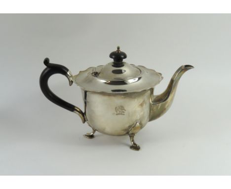 A silver teapot, by Mappin and Webb, Sheffield, 1938, circular form, the hinged cover with wooden disc finial, scroll border,