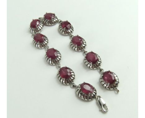 An 18ct white gold ruby set bracelet, the oval cut rubies in four claw settings, in decorative mounts, ruby total weight 32.2